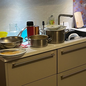 Küchenschränke und noch zu reinigendes Geschirr auf der Ablage.