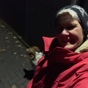 Eine Frau geht im dunkeln mit ihrem Hund spazieren.