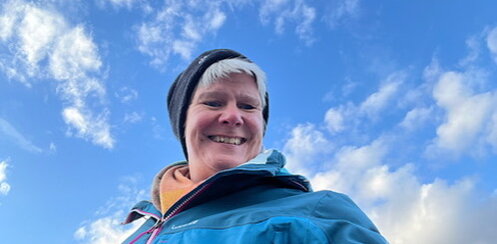 D3833053-2942-48C0-8B0A-90CA6561EB41_4_5005_c Claudia lacht in die Kamera und über ihr Wolken und blauer Himmel