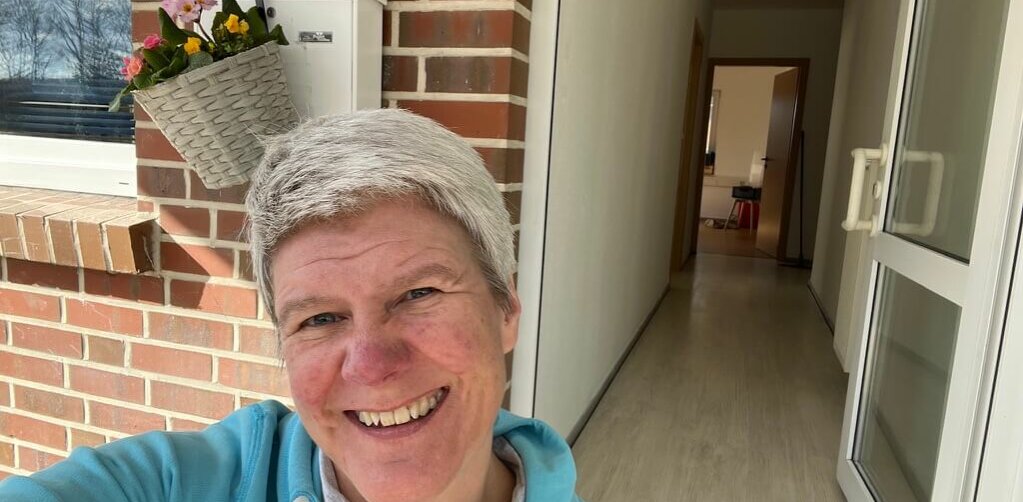 05599BA7-5F0C-4FD8-B184-0F5735CD184F_1_105_c Das Foto zeigt eine lachende Frau und im Hintergrund kann man in einen langen Flur reinschauen.