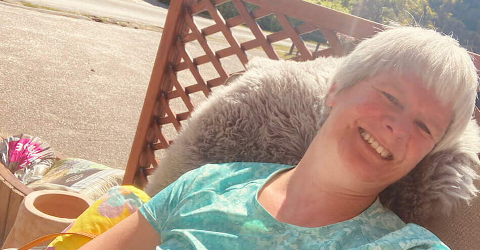 Eine Frau sitzt im Sessel und lacht.